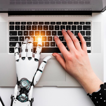 Pessoa utilizando notebook uma mão humana digitando e outra mão de robô.